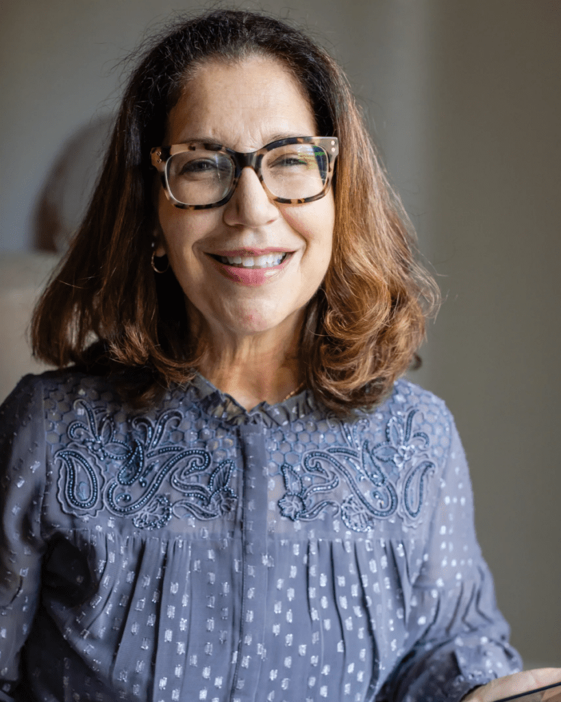 A woman with glasses smiling for the camera.